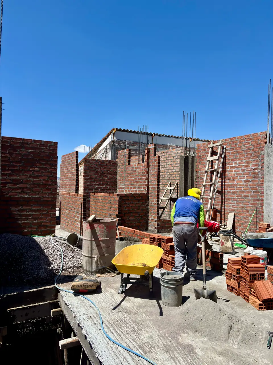 Worker at a building site in front of brick walls under construction